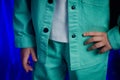 A fragment of underage clothes of a denim jacket and turquoise trousers with a white T-shirt on the model