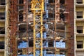 Fragment of an unfinished concrete and brick building under construction with scaffolding and a crane