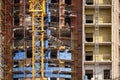 Fragment of an unfinished concrete and brick building under construction with scaffolding and a crane