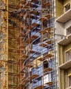 Fragment of an unfinished concrete and brick building under construction with scaffolding and a crane