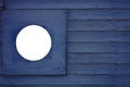 Fragment of a vertical wooden navy blue painted surface with a round empty hole for the image