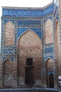 A fragment of a wall decorated with mosaics and ornaments with ancient wooden doors in the Gur Emir mausoleum in Samarkand,