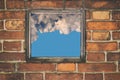 Fragment of the wall of an old house with a bricklaying of red brick and and view from small window with cloud sky Royalty Free Stock Photo