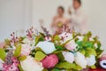 A fragment of a wedding decoration - rose flowers, the bride and groom drink champagne in the background, out of focus