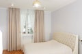 fragment of white bedroom with curtain, tulle, bed, pillow and nightstand closeup photo