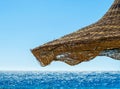 Fragment of a wicker beach umbrella against the backdrop of the sea and a clear blue sky Royalty Free Stock Photo