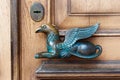 Fragment of wooden brown door with metal door-handle in the form of griffin or gryphon