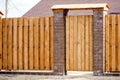 Fragment of a wooden brown modern fence with a wicket, close-up. Modern design ideas of a wooden fence