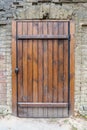 Fragment - a wooden door in an old warehouse. An element of architecture is an old strong simple door. Vertical photo.