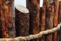 Fragment of a wooden fence made of tree trunks and rope. Close-up Royalty Free Stock Photo