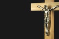 A fragment of a wooden illuminated crucifix against a black back