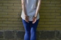 Fragment of a young criminal girl`s body with hands in handcuffs against a yellow brick wall background