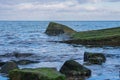 Fragments of cement slabs and large stones covered with green algae in the sea Royalty Free Stock Photo