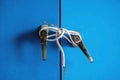 Fragments of white electric cable were tied to silver knob of steel cabinet doors. Old door locked with electric wire cable. Blue Royalty Free Stock Photo