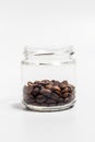 Fragrant coffee grains in a small glass jar on a white background