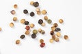 Fragrant colored peppercorns lies on a white background. A scattering of peppercorns