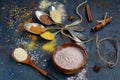 Fragrant cuisine. Colored spices in spoons, wooden bowl, cinnamon sticks and senena sesame and flax on a dark blue old background Royalty Free Stock Photo