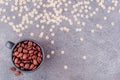 Fragrant grains of black coffee in a black glass on a gray concrete background