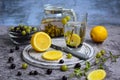 Fragrant herbal tea in a glass teapot with currant and gooseberry berries and a glass on a wooden stand, knife, lemon slices on a