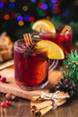 Fragrant, hot punch or mulled wine for Christmas in a glass on a wooden board and branches of a Christmas tree on the background Royalty Free Stock Photo