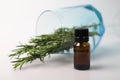 fragrant medicinal evergreen rosemary on a light background with a transparent glass and a jar of hair oil. medical