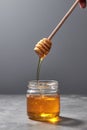 Sweet flower natural honey dripping to a glass jat with yellow transparent dessert on a gray background. Rosh hashanah