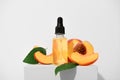 Fragrant peach essential oil on a white stand. An aromatic fruit spa oil for skin care. Alternative homeopathic medicine product Royalty Free Stock Photo