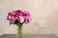 Fragrant peonies in vase on table against color background. Beautiful spring flowers Royalty Free Stock Photo
