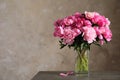 Fragrant peonies in vase on table against color background. Beautiful spring flowers Royalty Free Stock Photo