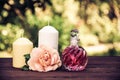 Fragrant rose oil in a beautiful glass bottle. Pink elixir, candles and flowers. Spa concept. Vintage tinting