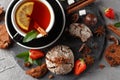 Fragrant tea in a black cup on a black plate with biscuits, lemon, cinnamon and fruits Royalty Free Stock Photo