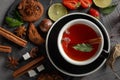 Fragrant tea in a black cup on a black plate with biscuits, lemon, cinnamon and fruits Royalty Free Stock Photo