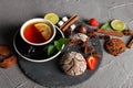 Fragrant tea in a black cup on a black plate with biscuits, lemon, cinnamon and fruits Royalty Free Stock Photo