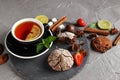 Fragrant tea in a black cup on a black plate with biscuits, lemon, cinnamon and fruits Royalty Free Stock Photo