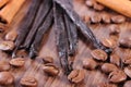 Fragrant vanilla, cinnamon sticks and coffee grains on wooden surface