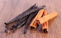 Fragrant vanilla and cinnamon sticks on wooden surface plank