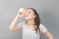 Fragrant, warming coffee in a glass. Young woman drinks hot drink on gray background