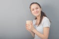 Fragrant, warming coffee in a glass. Young woman drinks hot drink on gray background