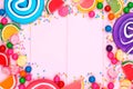 Frame of assorted colorful candies against pink wood