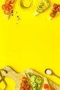 Frame of avocado sandwiches on yellow kitchen table top space for text