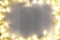 Frame of beautiful glowing Christmas lights on white wooden table, top view. Space for text Royalty Free Stock Photo