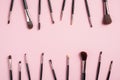 Frame of black professional makeup brushes on pink background. Flat lay, top view. Makeup shop banner mockup