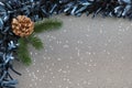 Frame with blue tinsel, a pine cone and fresh pine brunches, and sparkling confetti stars spread against a silver gray background Royalty Free Stock Photo