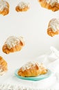 Frame or border of flying croissants with almond flakes and powdered sugar on white background. Breakfast food levitation concept