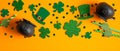 Frame border of shamrock four leaf clovers, Irish elf hats, pots of gold, confetti. Saint Patrick`s day symbols on orange Royalty Free Stock Photo