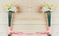 Frame of bouquets of daffodils flowers tied with pink ribbon on a natural wooden background with copy space