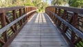 Frame Bridge with wood deck and rusty metal railing over a lake with grassy shore