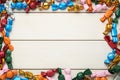 Frame of candies in colorful wrappers on beige wooden table, flat lay. Space for text Royalty Free Stock Photo
