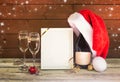 Frame, champagne glasses, champagne bottle with  Santa hat and christmas decorations on aged wooden table. Royalty Free Stock Photo