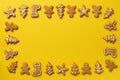 Frame of Christmas gingerbread cookies on yellow background with copy space. Pattern of gingerbread men, snowflake, star, fir-tree Royalty Free Stock Photo